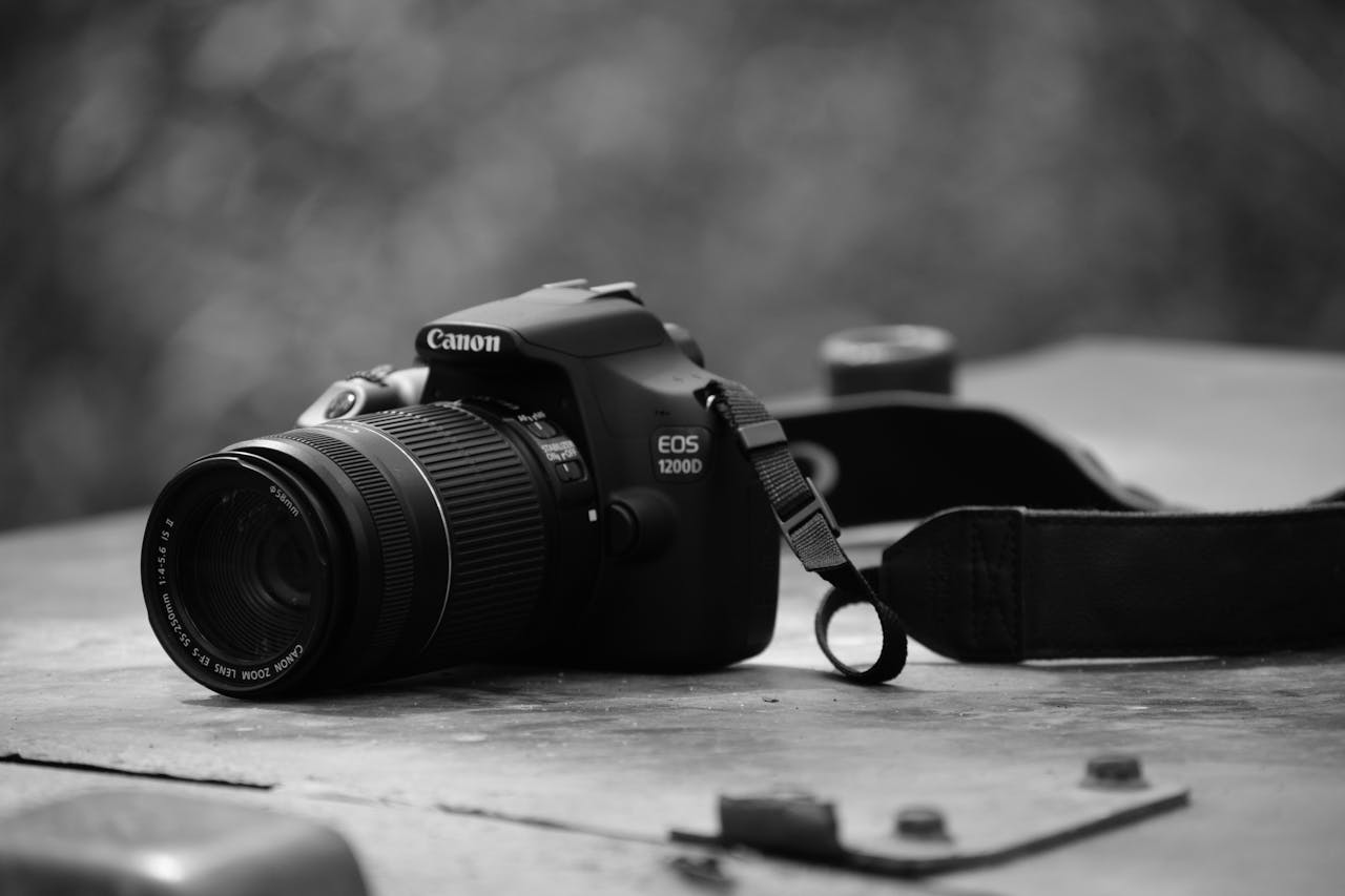 Monochrome close-up of DSLR camera placed on a textured outdoor table.