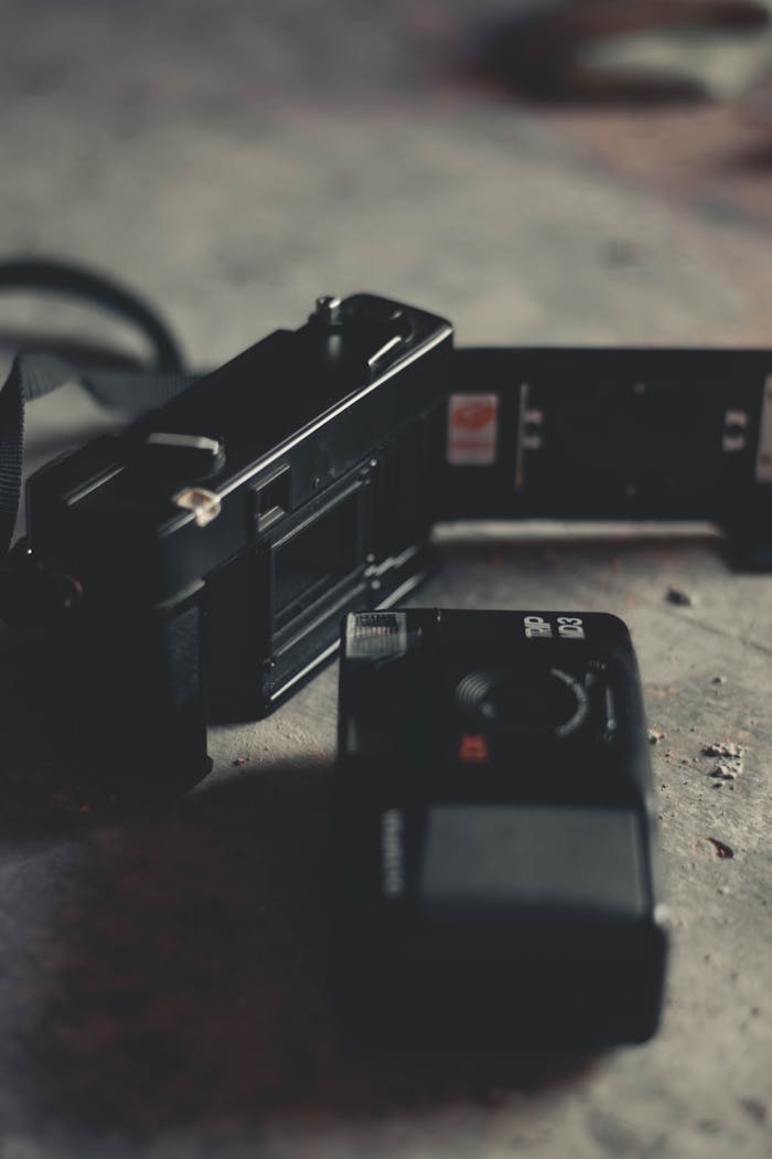 Classic film camera with open back displaying film roll, on a textured surface.